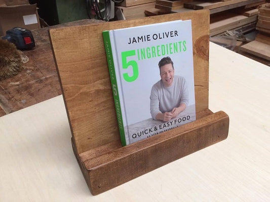 Handmade rustic wooden cookbook stand holding Jamie Oliver’s 5 Ingredients recipe book, crafted by Spire Carpentry UK.